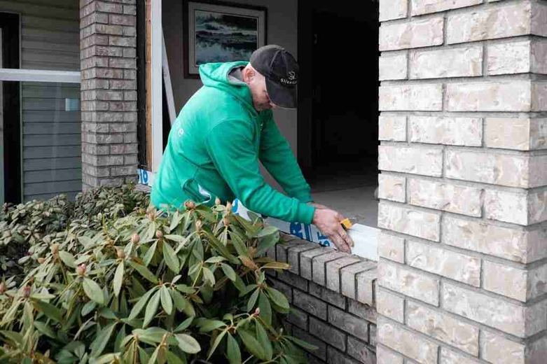 A SilverLine installer working over a brick window sill