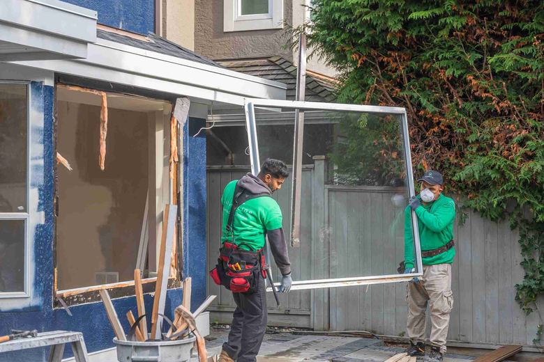 Two SilverLine crew carrying a window frame across a front yard