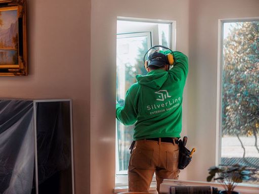 A SilverLine installer checking a finished window from inside a living room